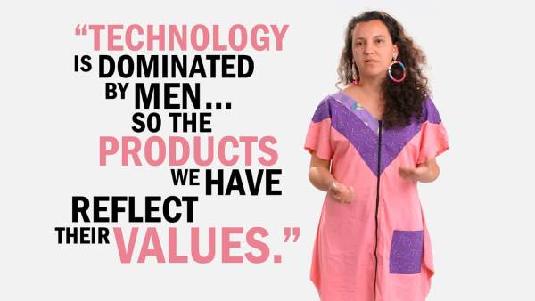 Steffania Costa has long brown curly hair and is wearing colorful looped earrings and violet and pink jumpsuit. She's standing next to copy that reads, "Technology is dominated by men... so the products we have reflect their values."