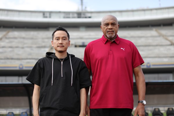 A photograph of two men standing, looking straight at the camera