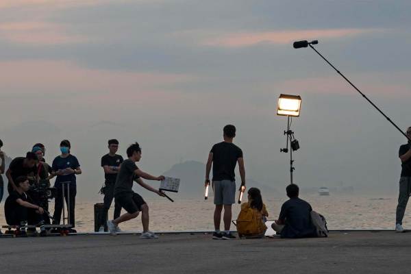 Group of Asian film staff on set filming in the evening along a shoreline in Hong Kong, China.