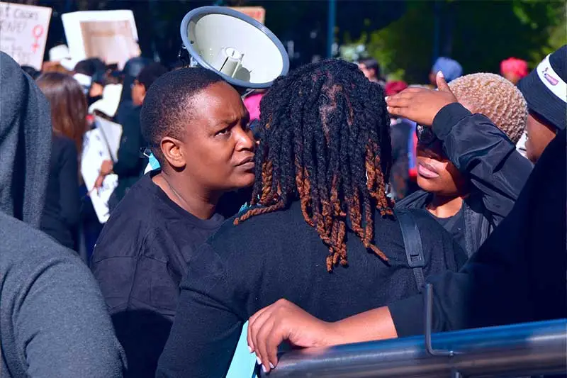 Demonstrators holding signs advocating for the end of gender-based violence in South Africa.