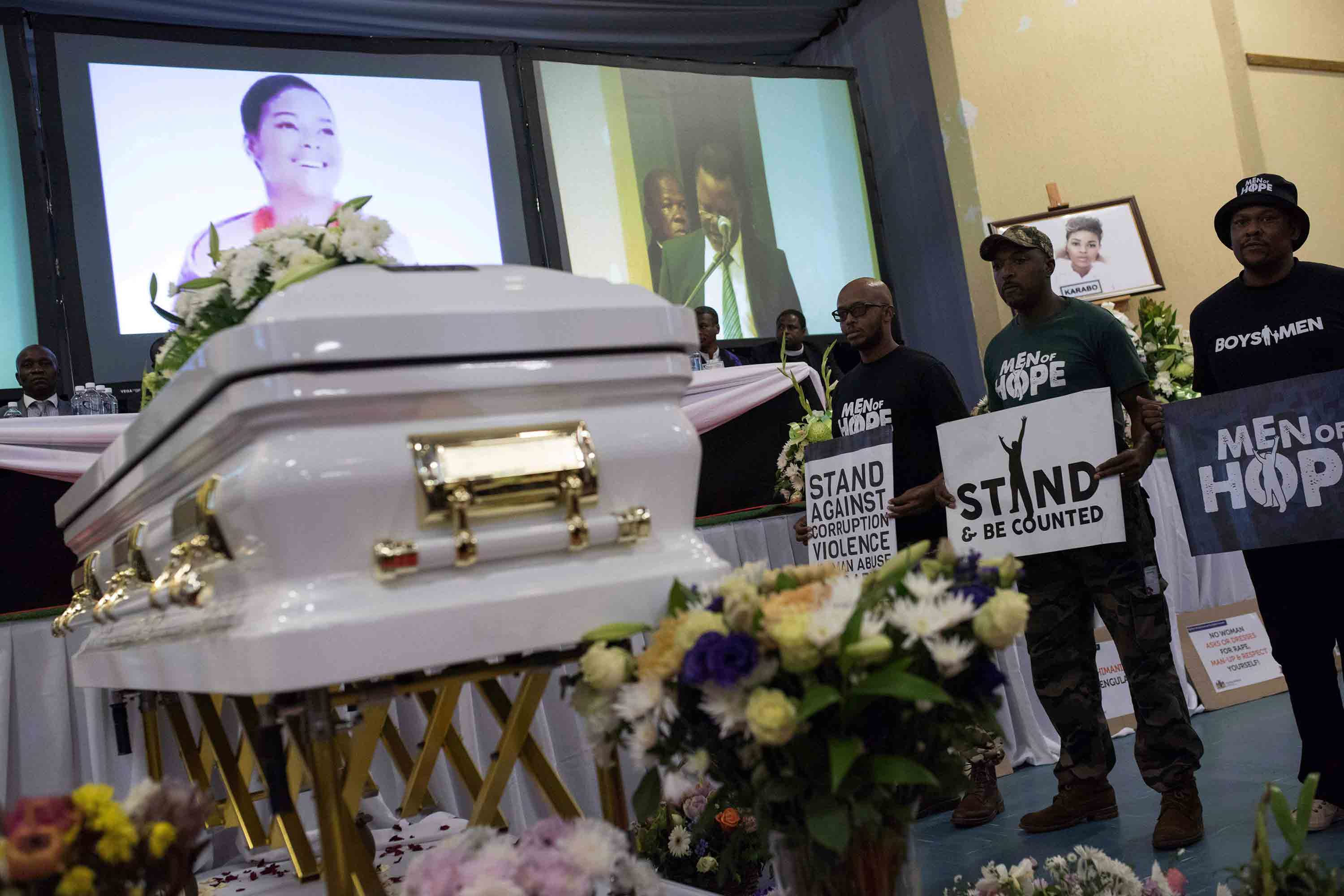 Demonstrators hold up signs against GBV at the funeral of  Karabo Mokoena.