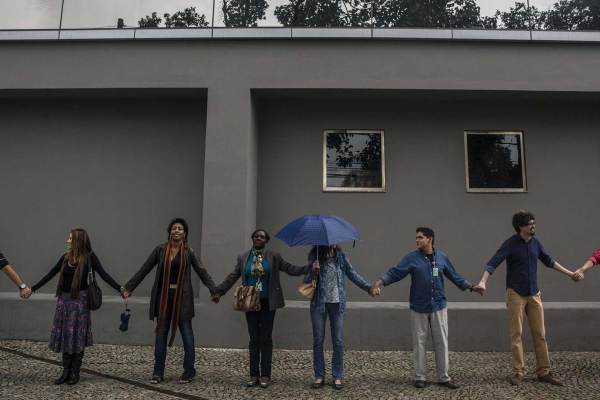 A group of people hold hands as they stand in a line.