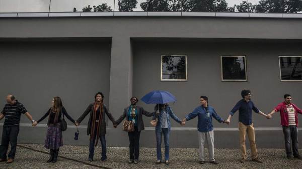 A group of people hold hands as they stand in a line.