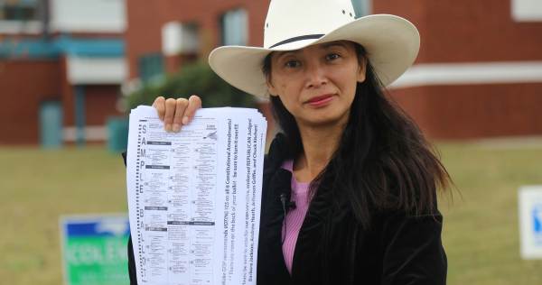 A photograph of a woman holding up forms