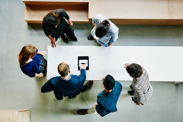 Overhead view of business colleagues discussing a project on a digital tablet.