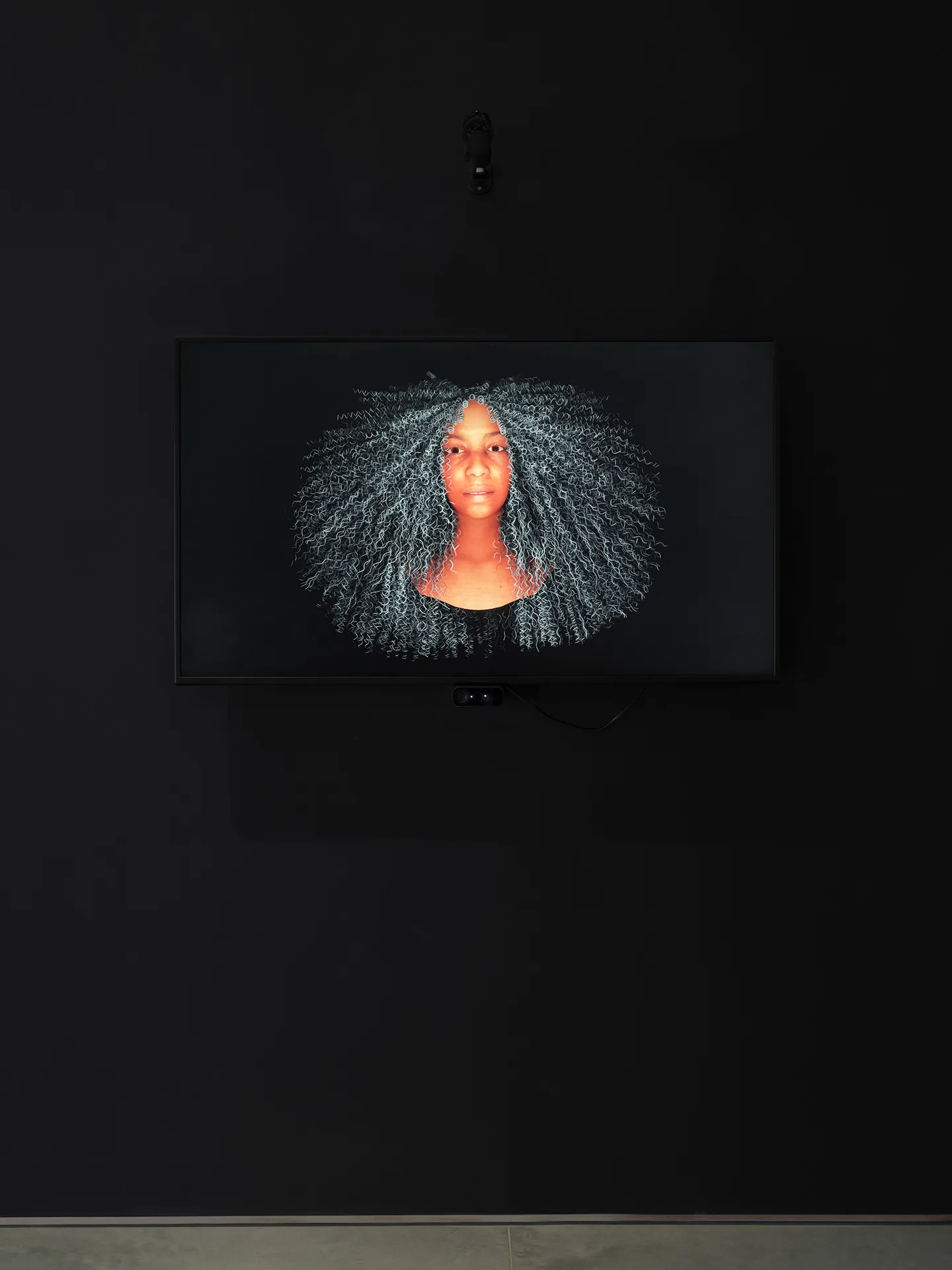 Image of a Black woman’s head on a black background. The woman has saturated orange skin and long white curly hair.