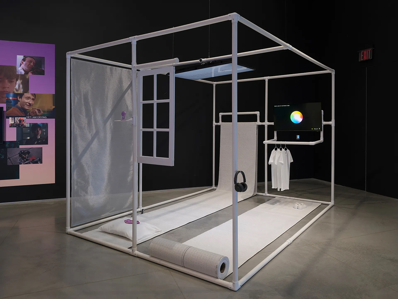 Room sized immersive installation shaped like a three dimensional rectangular frame. There are two carpet runners on the floor, and two video monitors mounted on the wall and on the ceiling.