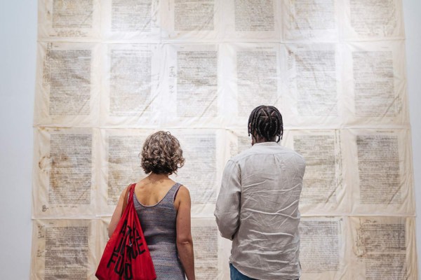 A woman and man look at printed text on a wall