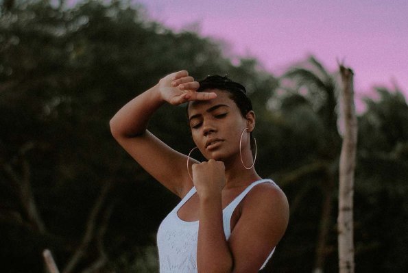 A woman in white top and shorts standing against a purple sky.