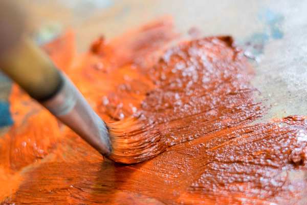 Orange paint being applied with brush.