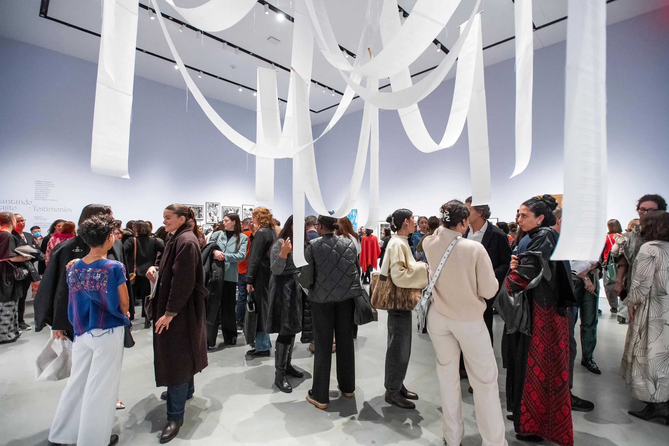 A room filled with people and white paper streamers hanging from the ceiling.