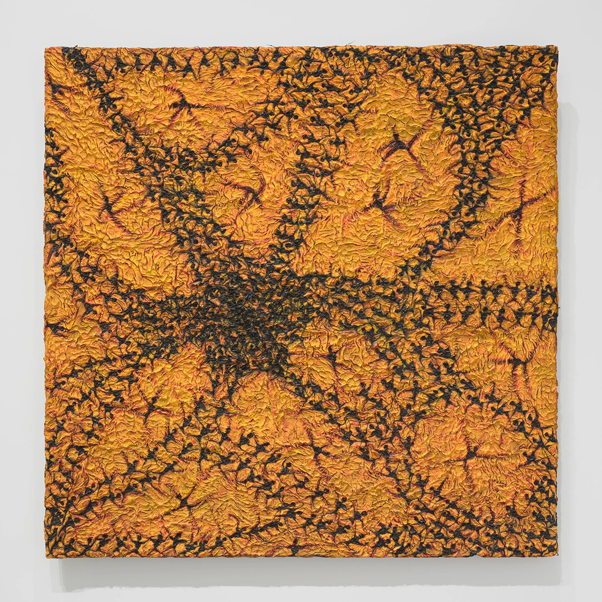 Abstract painting with black paper on an orange surface where human symbols form an organic pattern.
