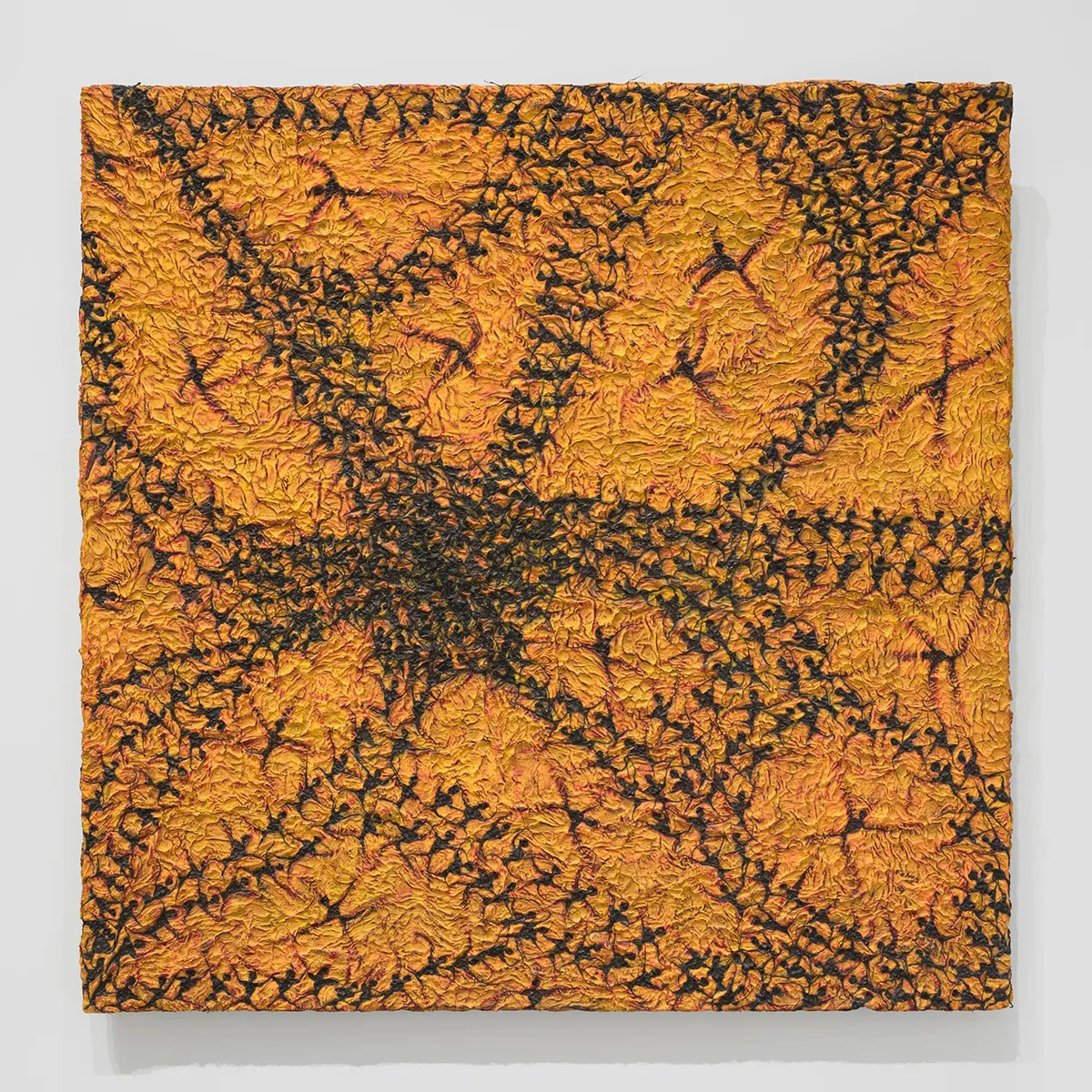 Abstract painting with black paper on an orange surface where human symbols form an organic pattern.