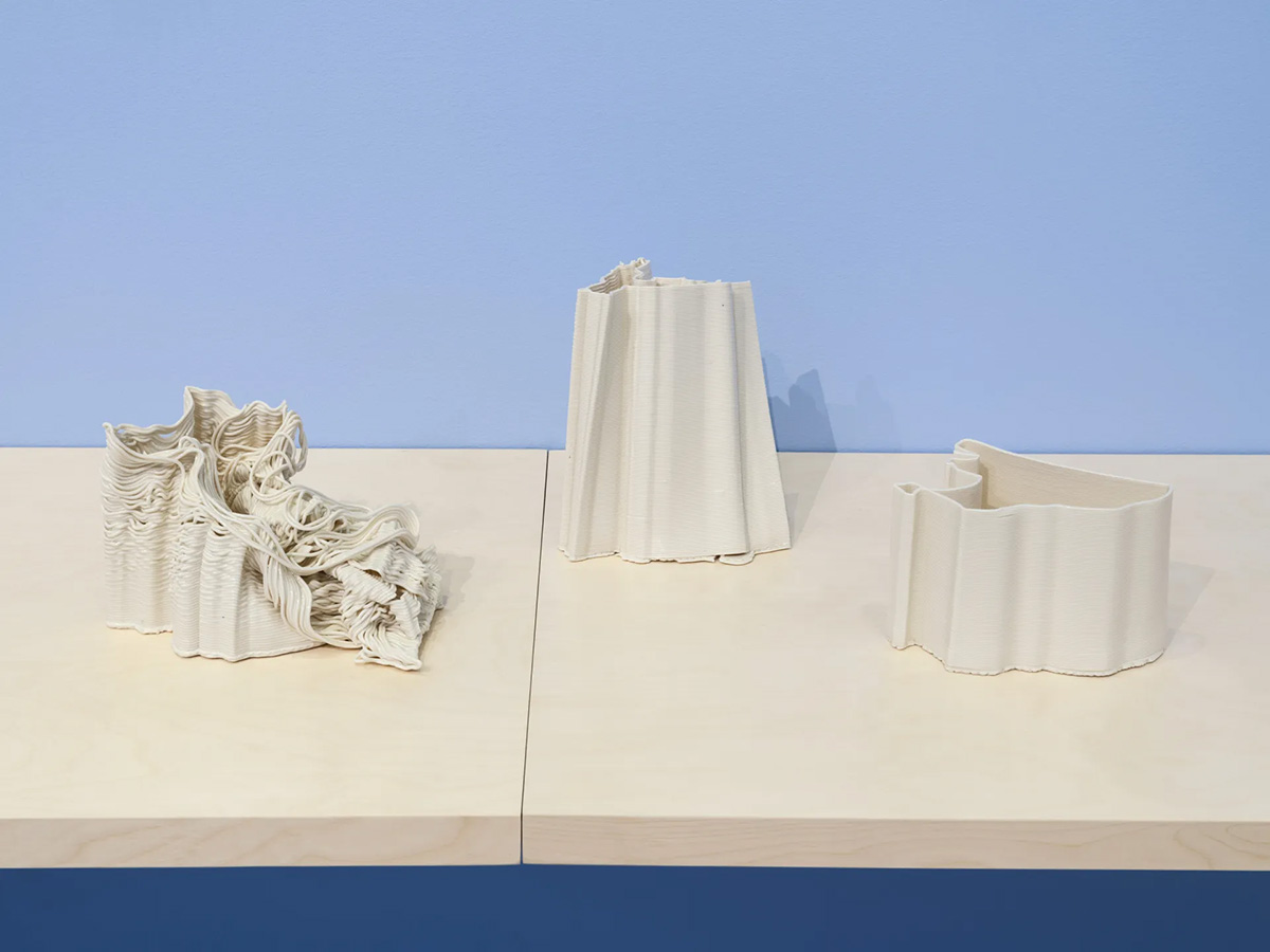 Three coiled ceramic vessels on a light wood desk.