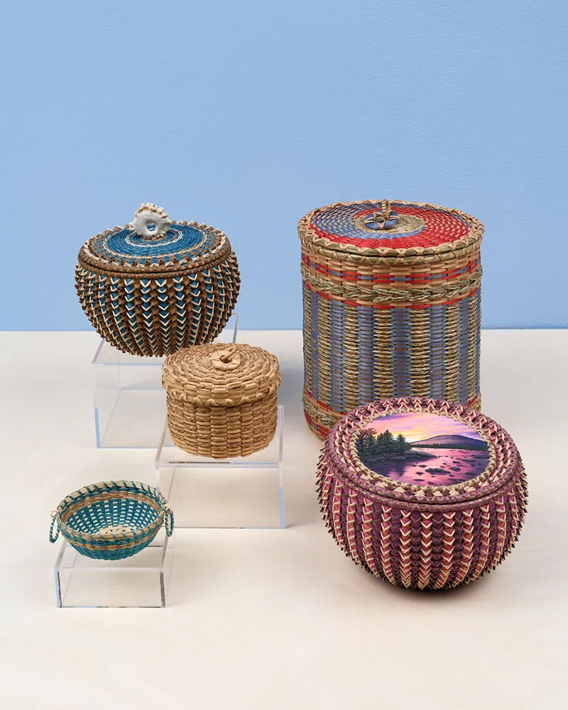 Five colorful woven baskets on a wooden shelf.