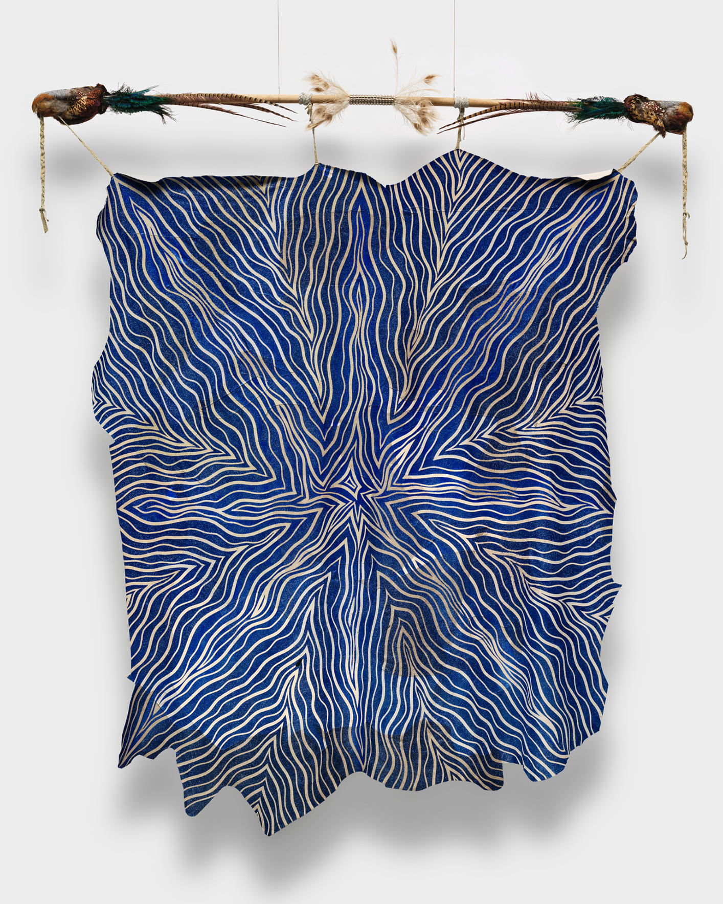 A star-designed fabric painting hung by a pole decorated with bird feathers