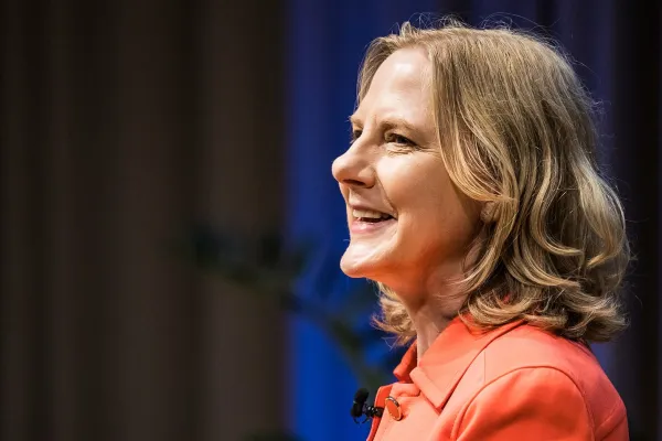 A candid photo of Heather Gerken in a bright orange blazer smiling.