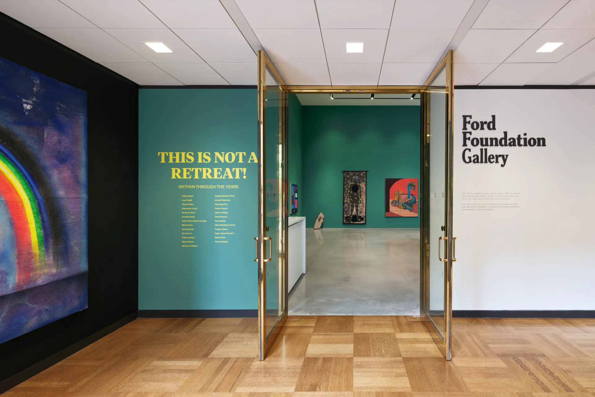 Bronze-framed doors open showing a glimpse into the gallery exhibition titled “THIS IS NOT A RETREAT!”