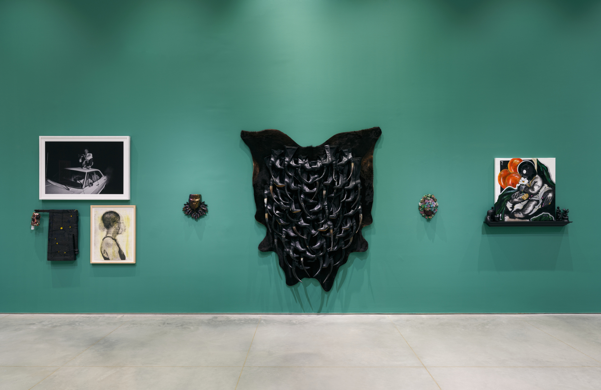 A wall with various sculptural artworks - some works are made of glass, boots, painted canvas and more.