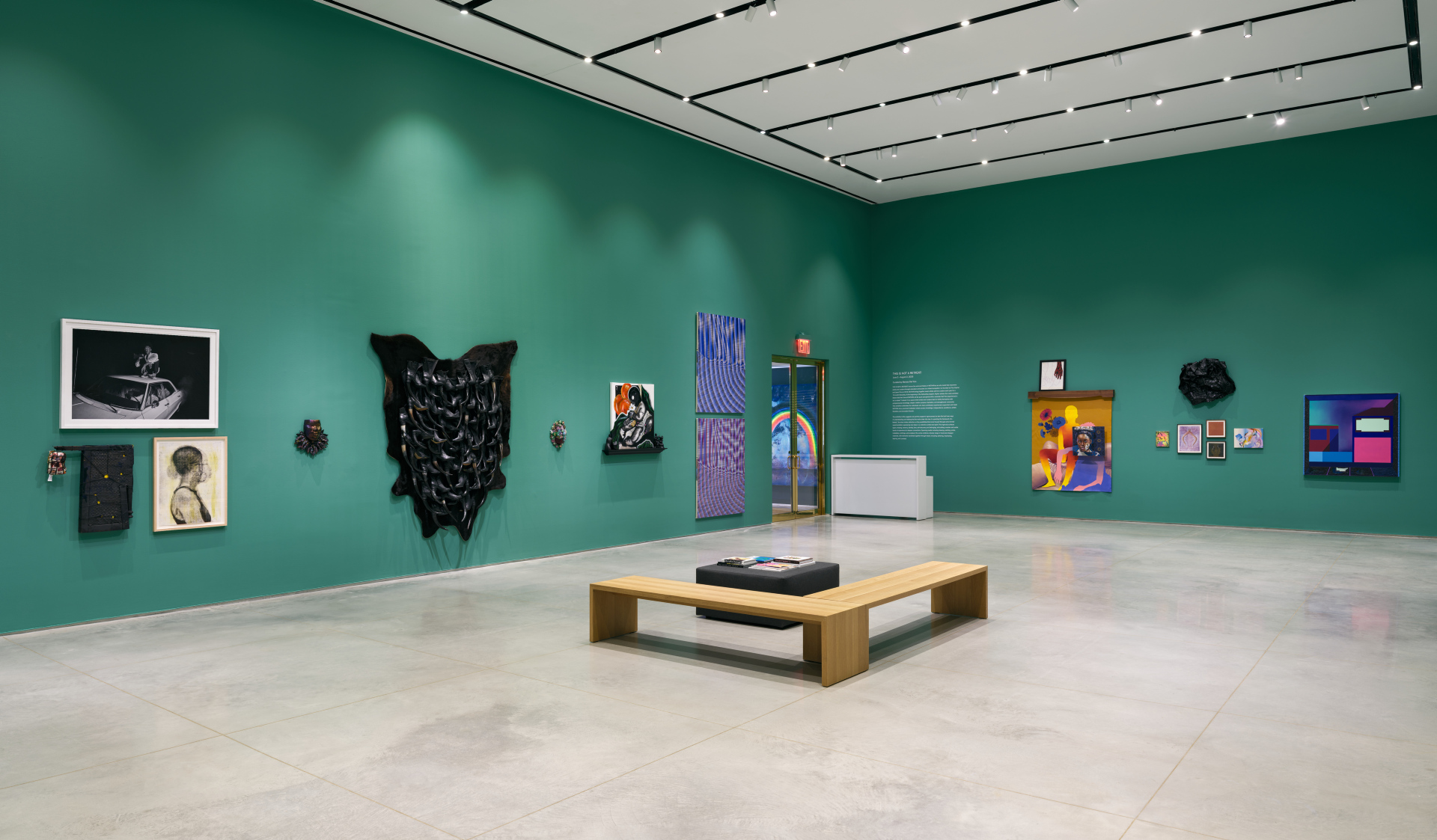 A diagonal wide-shot installation view of a gallery exhibition that features artworks salon-style.