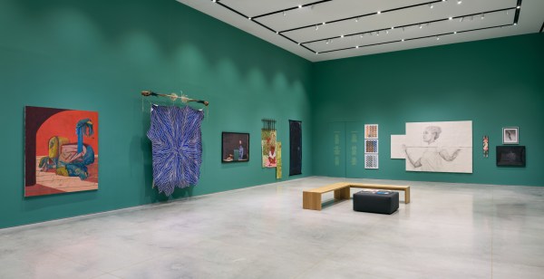 A diagonal wide-shot installation view of a gallery exhibition that features artworks salon-style.