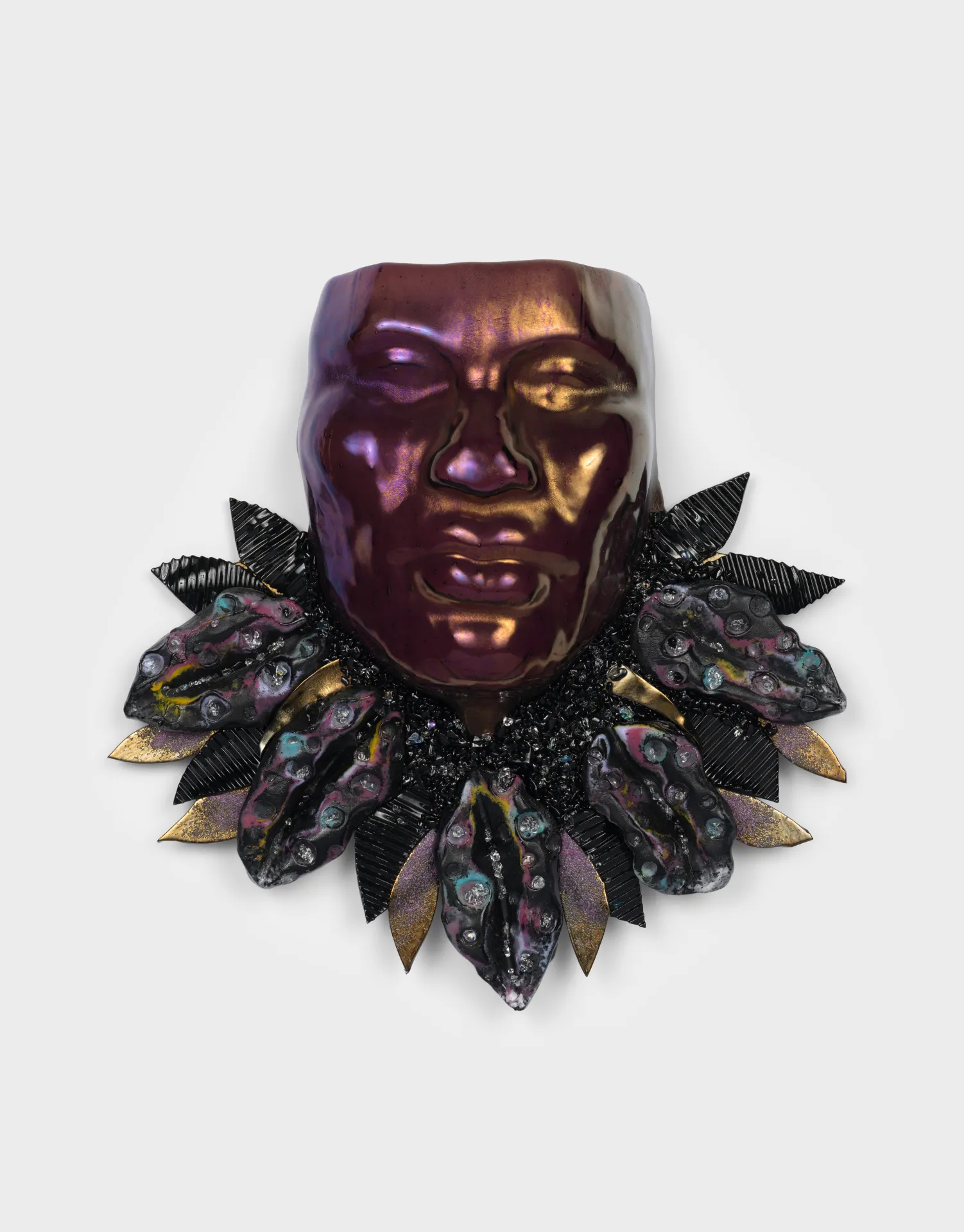 Glass mask of a face with a collar of leaves extending from the chin.