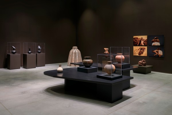 An installation view of a gallery exhibition featuring various ceramic sculptures and clay pots that differ in size, texture and color.