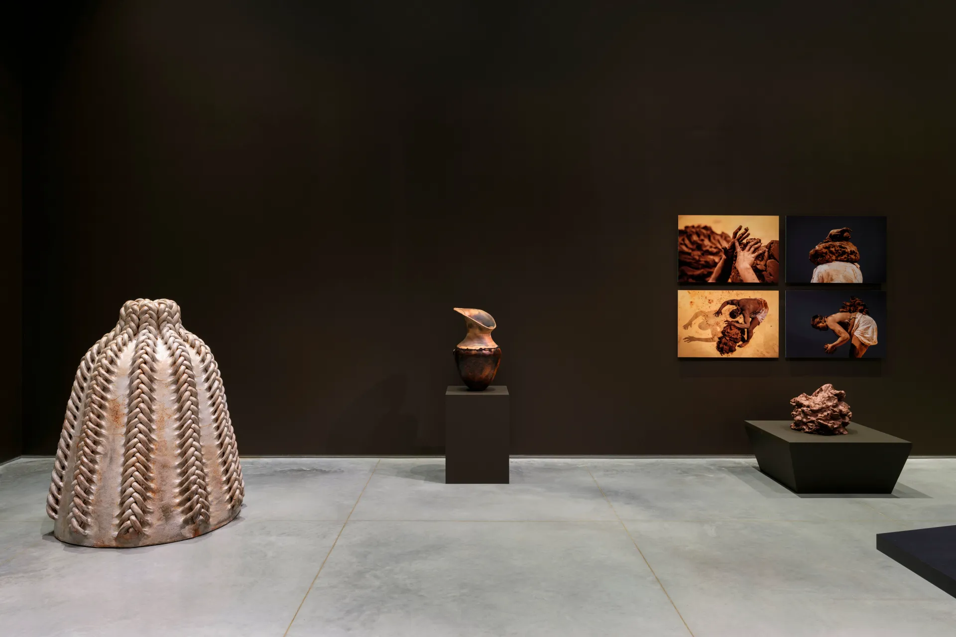 Various artworks relating to clay including a five-feet tall sculpture, a vase, a mound of clay, and four performance photos.