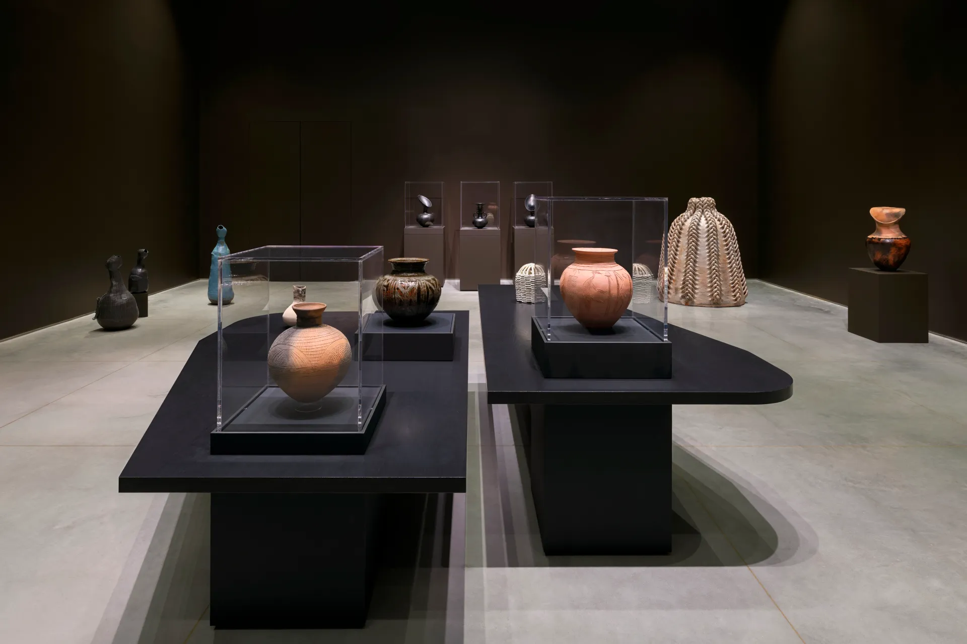 An installation view of a ceramic gallery exhibition behind a table with various clay sculptures.