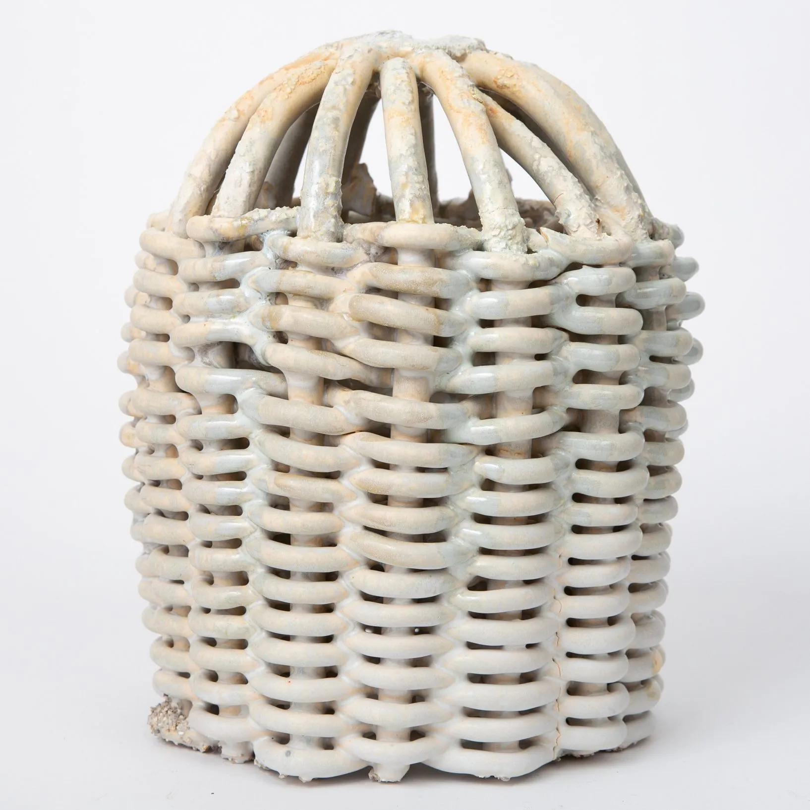 A ceramic vessel with coils interwoven like a wicker basket. The coils are joined together, forming an interlocking arched top.