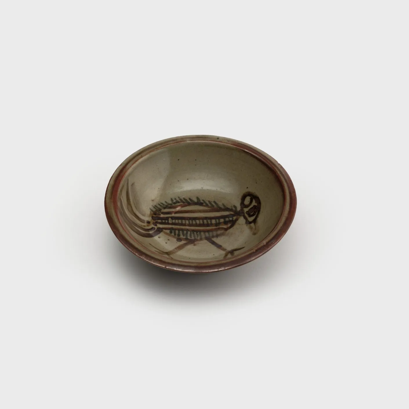 Circular ceramic dish with a simple, bold line glaze painting of a bird.