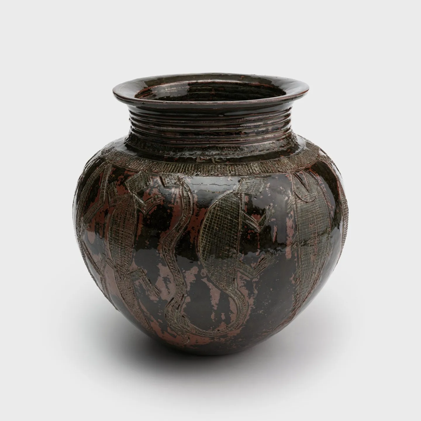 A clay pot with a tapered neck and animal motifs carved into the surface, including a lizard, a turtle, a snake, and a fish.