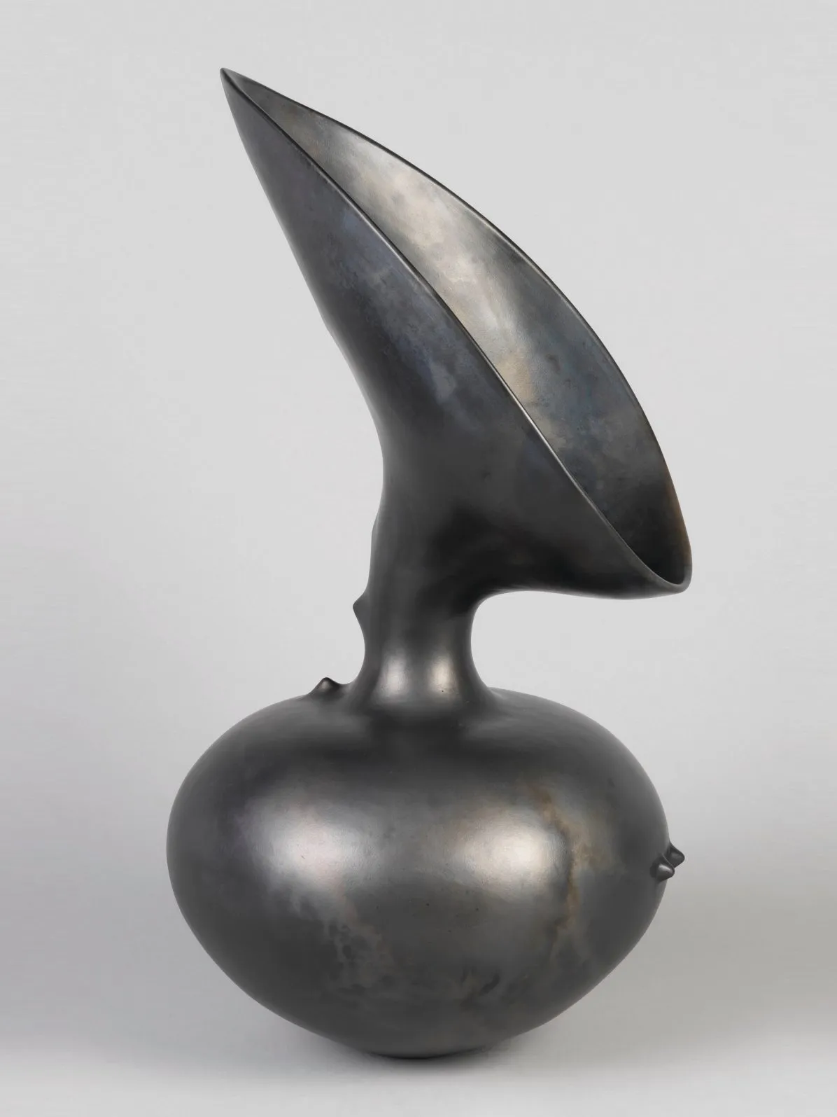 A large, silvery black ceramic vessel with a body in the shape of a horizontal oval narrows into a neck that opens into a tall teardrop-shaped mouth.