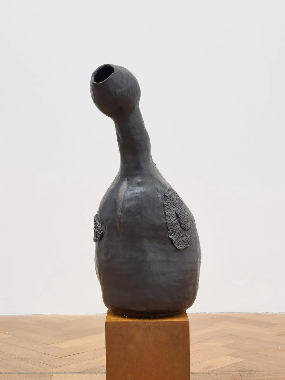 A ceramic sculpture with a lumpy body and long protruding neck, which bulges into an egg shape towards the opening. The vase is reminiscent of a gourd or goose.