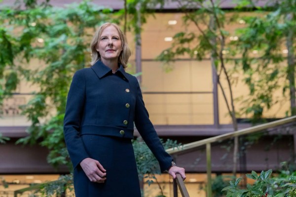Ford Foundation president Heather Gerken in a navy coat with gold buttons standing in the foundation's atrium garden. Keywords: non-profit leader, philanthropy, law, justice.