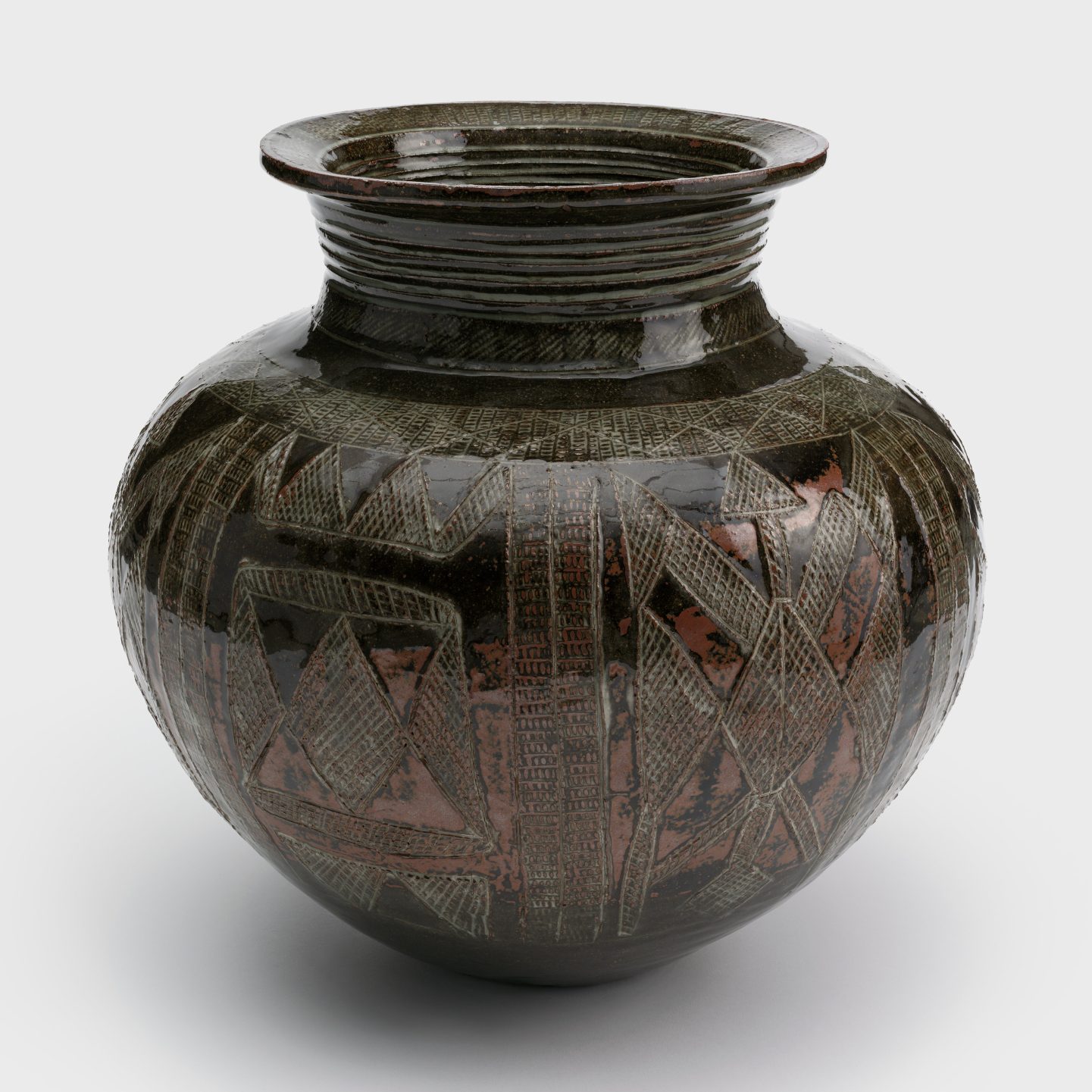 A glazed ceramic jar with a coiled neck and geometric designs made up of thin incised crosshatching throughout.
