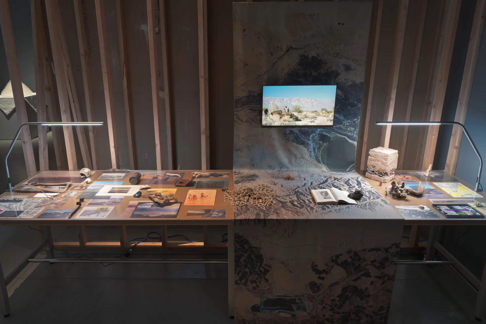 A table installation featuring an arrangement of texts, photographs, and archival objects concerning a desert environment.