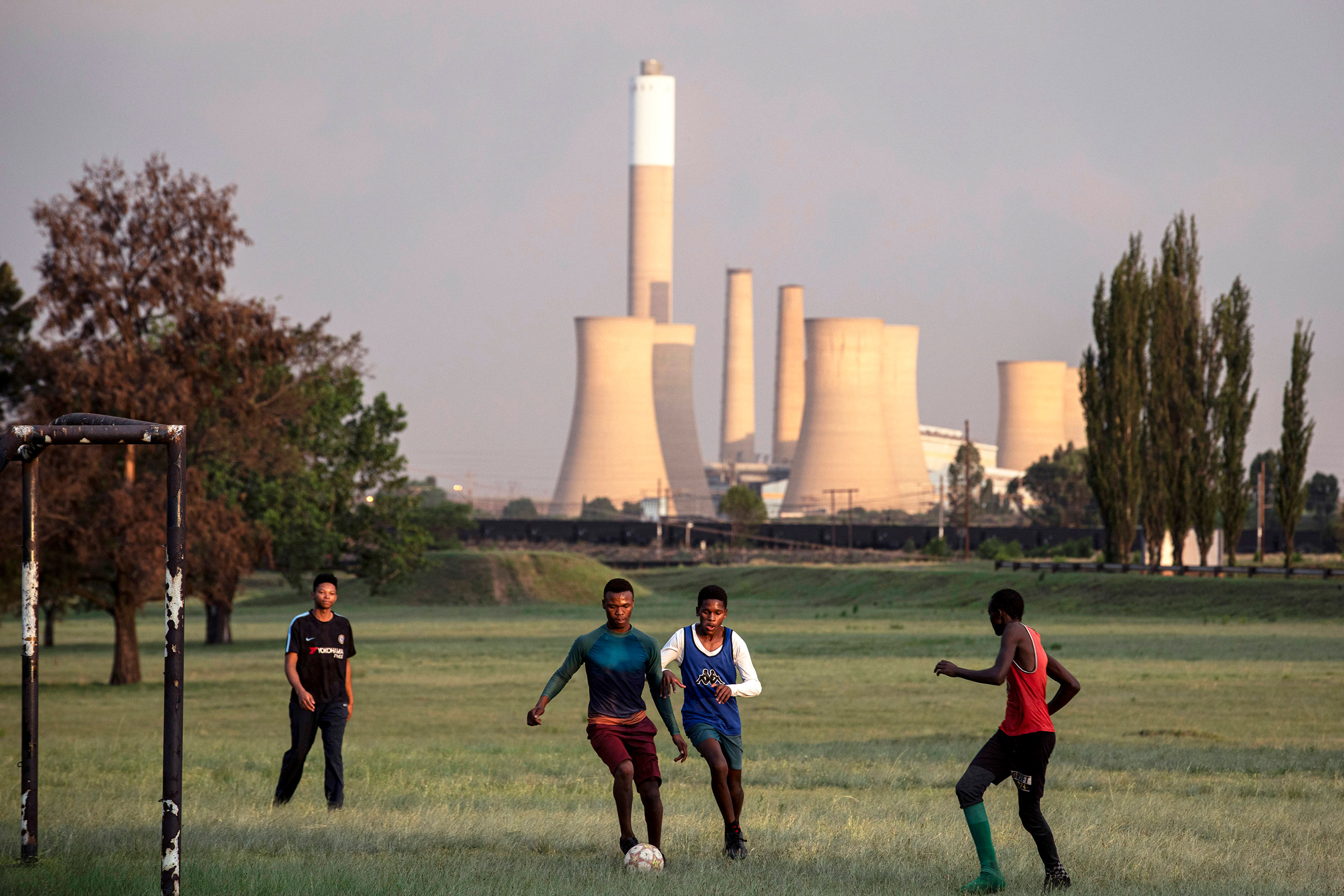 Young people play soccer on a field in Blinkpan, Mpumalanga Province, South Africa. The nearby coal mine Koornfontein was closed, leaving many people unemployed.