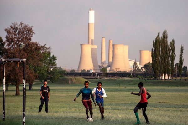 Young people play soccer on a field in Blinkpan, Mpumalanga Province, South Africa. The nearby coal mine Koornfontein was closed, leaving many people unemployed.