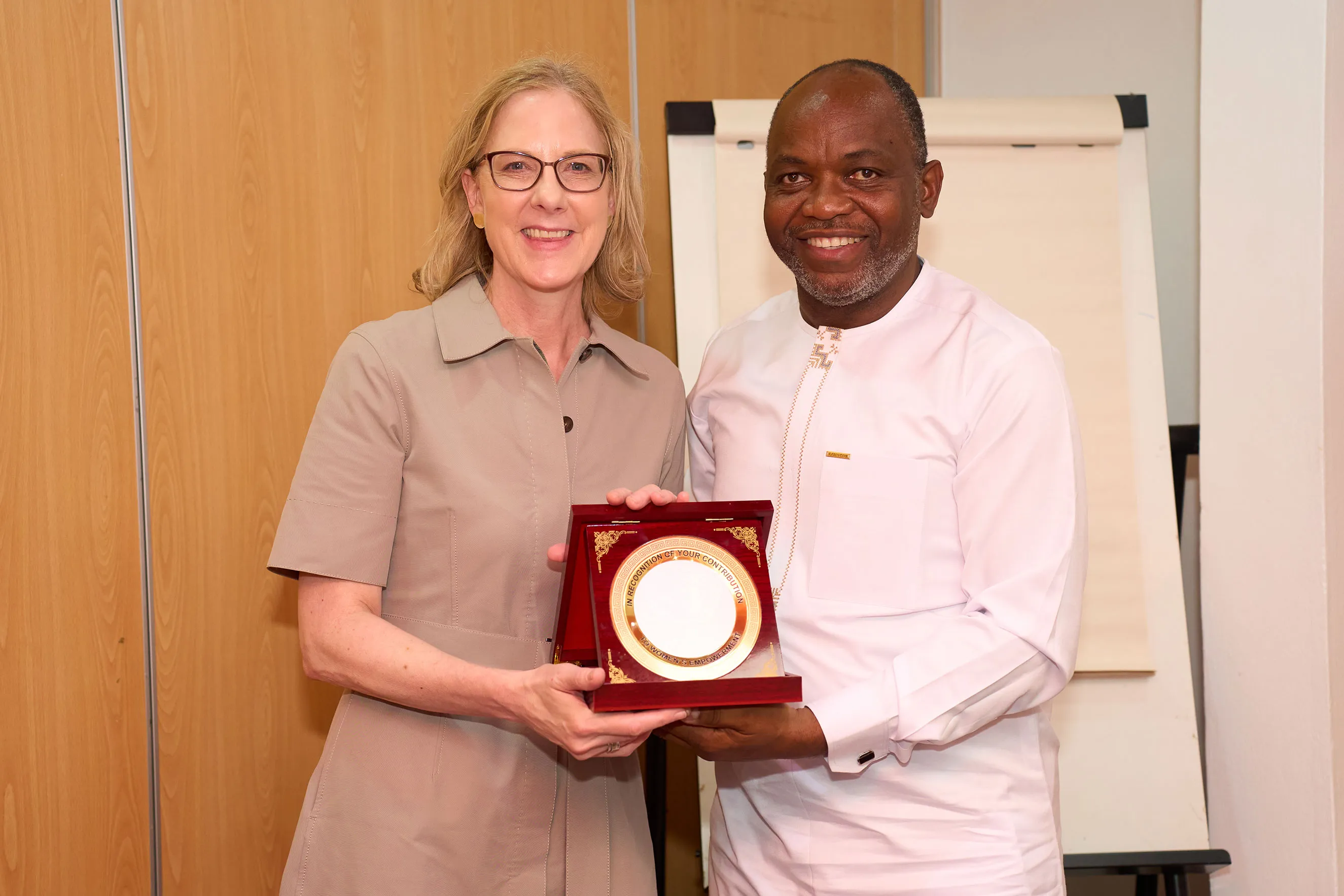 Alt Text: Heather Gerken and a Nigerian leader smile while holding a commemorative award plaque together. This image captures a moment of formal recognition, partnership, and mutual appreciation during a strategic leadership visit to Nigeria, highlighting collaborative efforts in global philanthropy.