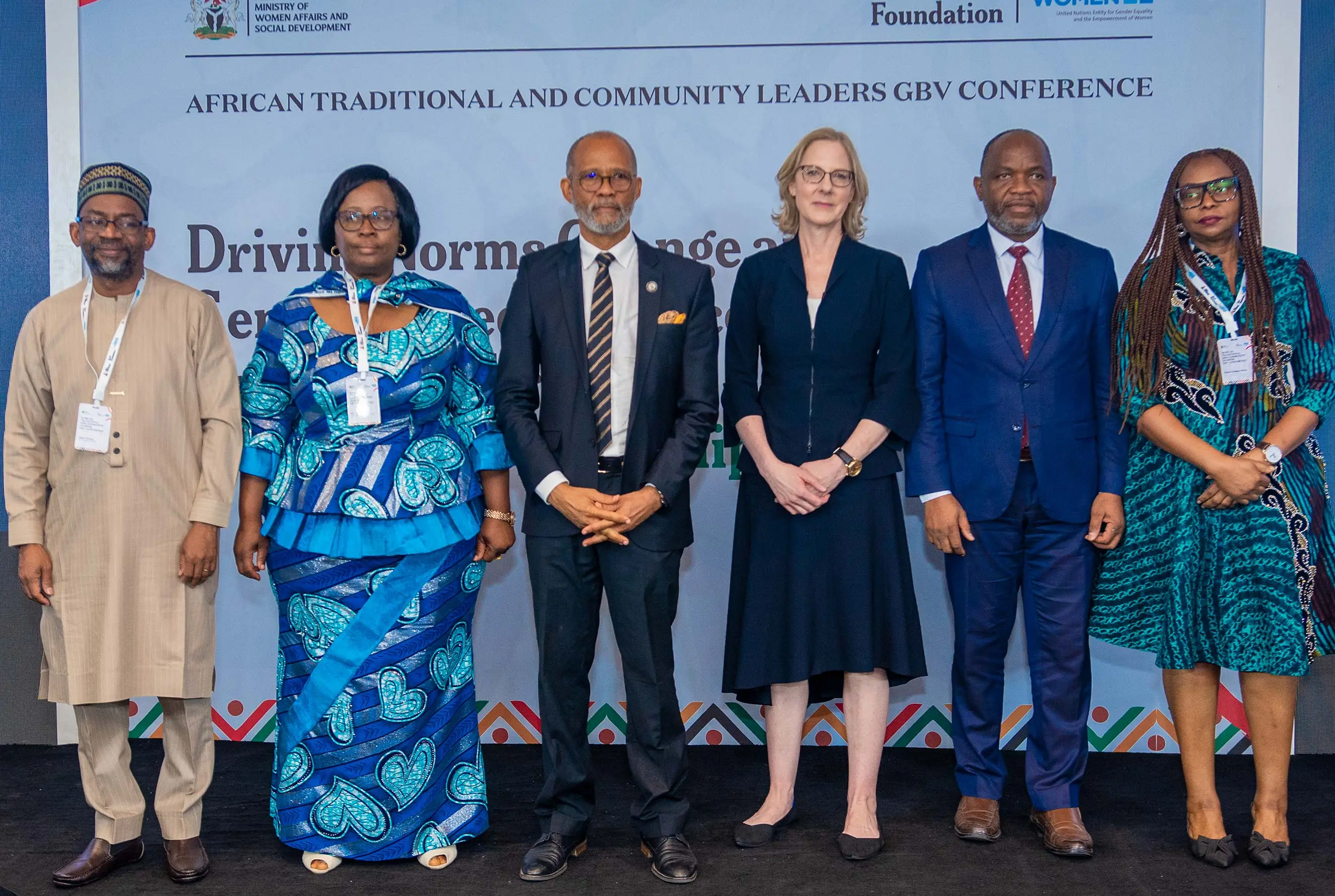 Six diverse leaders in formal and traditional attire stand before a banner at the African Traditional and Community Leaders GBV Conference. This image captures a strategic partnership between the Ford Foundation and UN Women to drive social change and prevent gender-based violence.