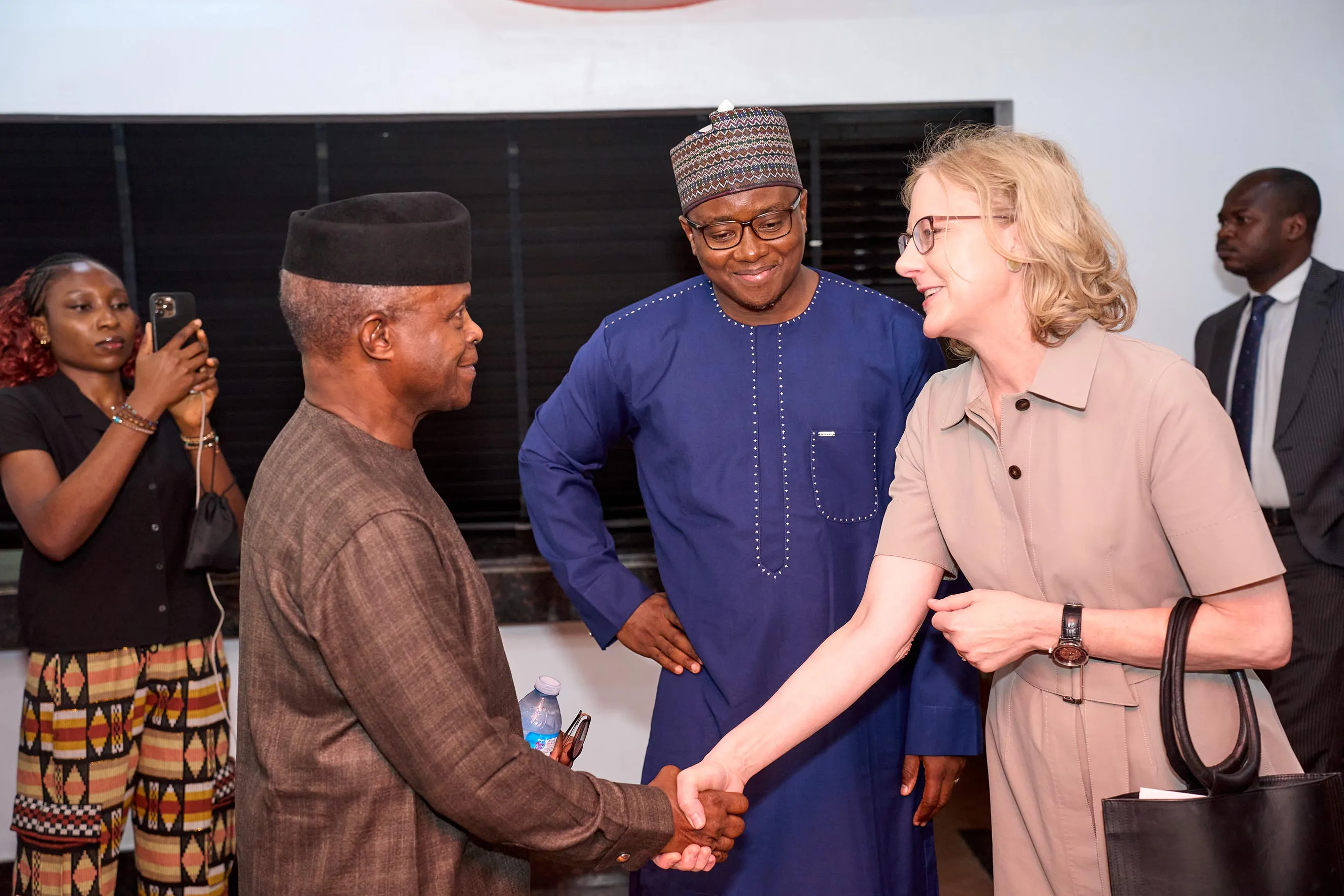 Alt Text: Heather Gerken warmly shakes hands with a Nigerian leader in traditional attire during a strategic visit. This candid moment highlights diplomatic engagement, local leadership, and international partnership aimed at fostering collaborative social impact and strengthening community ties in Nigeria.