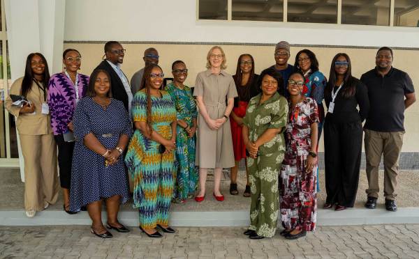 A diverse group of fifteen professionals, including international and local leaders, pose together outdoors during a visit to Nigeria. This image highlights global leadership, local empowerment, and collaborative social impact within a professional and community-focused context.