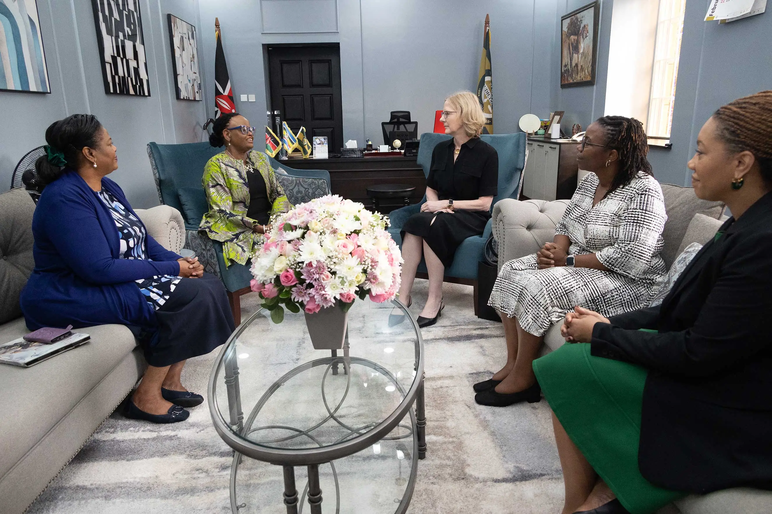 Five women in business attire engage in a formal meeting, seated in a plush office setting with a floral centerpiece. This image illustrates international cooperation, diplomatic dialogue, and professional female leadership during a strategic visit to Nairobi.