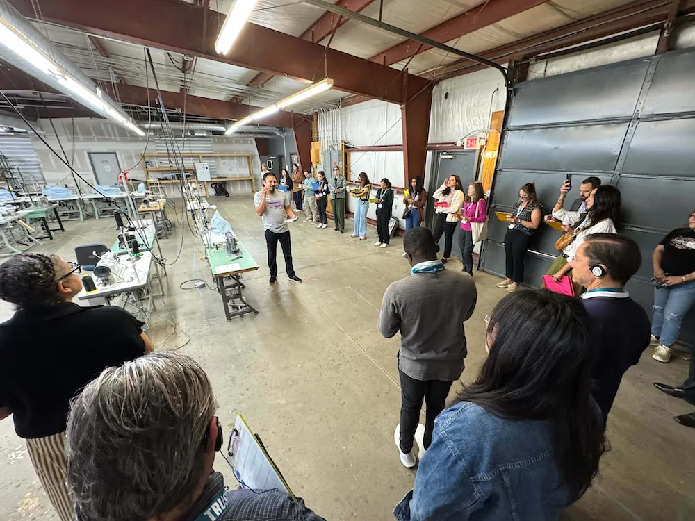 An aerial view of a vibrant rural community farm, featuring rows of lush crops, a central barn, and an outdoor gathering space. This image illustrates sustainable agriculture, community-led development, and local food systems as part of a rural civic hub in America.