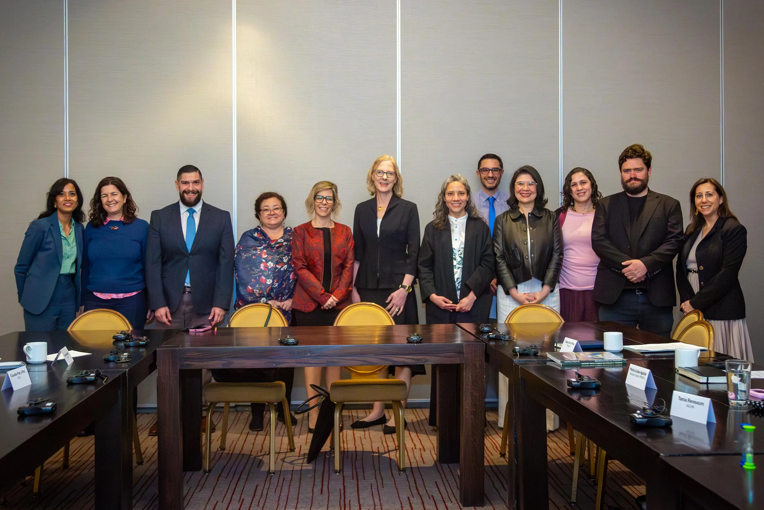 Twelve diverse staff members stand together behind a large wooden conference table in a meeting room. This high-quality photograph humanizes the foundation’s work, capturing a moment of collaboration and partnership during a regional office visit.