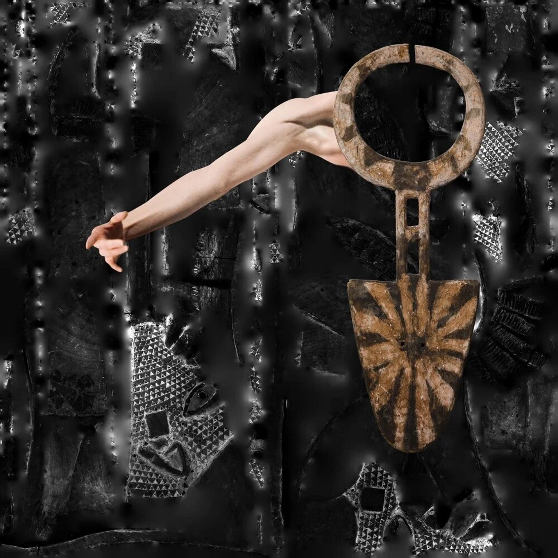 An abstract collage of a muscular white arm connected to anAfrican artifact in the shape of a spade and made of earthen materials, against a dark, textured background.