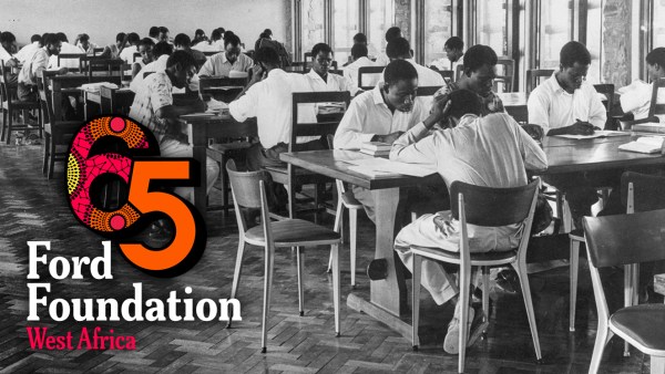 An archival black and white photograph of West African students studying at large wooden desks in a library or classroom hall. The colorful Ford Foundation West Africa 65th anniversary logo is superimposed in the lower left corner.