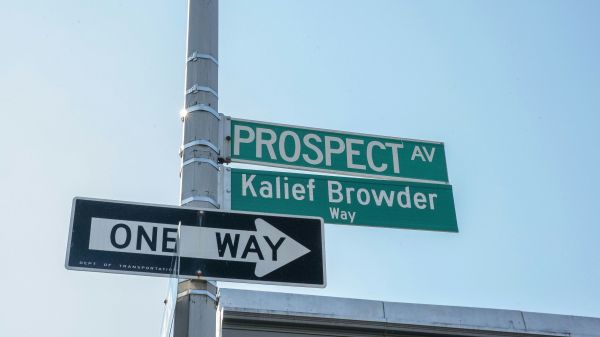 Green street signs on a metal pole for Prospect Av and Kalief Browder Way with a black One Way arrow sign below
