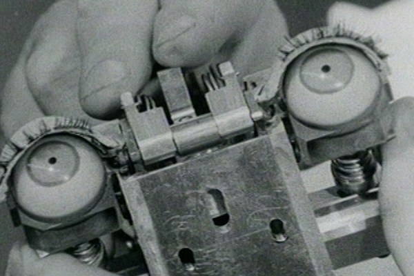 Extreme close-up of hands holding a complex mechanical animatronic eye mechanism with artificial eyeballs and eyelashes